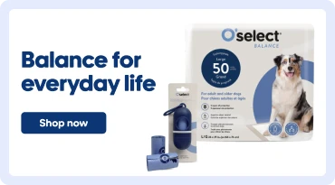 Promotional banner for O’select Balance pet products. On the left, the text “Everyday balance” appears above a “Shop Now” button. In the center, a bag of dog food and blue pet accessories are displayed. On the right, an O’select Balance cat litter box sits beside an orange-and-white cat in a bright indoor setting.